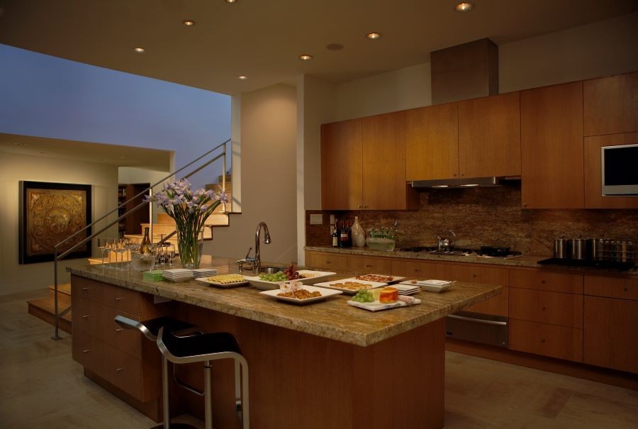 A softly illuminated kitchen with appetizers and wine setup on the island.