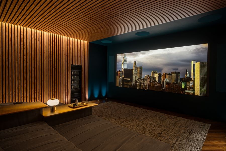 A home theater with a large movie screen displaying a cityscape and in-ceiling speakers powered by Marantz.