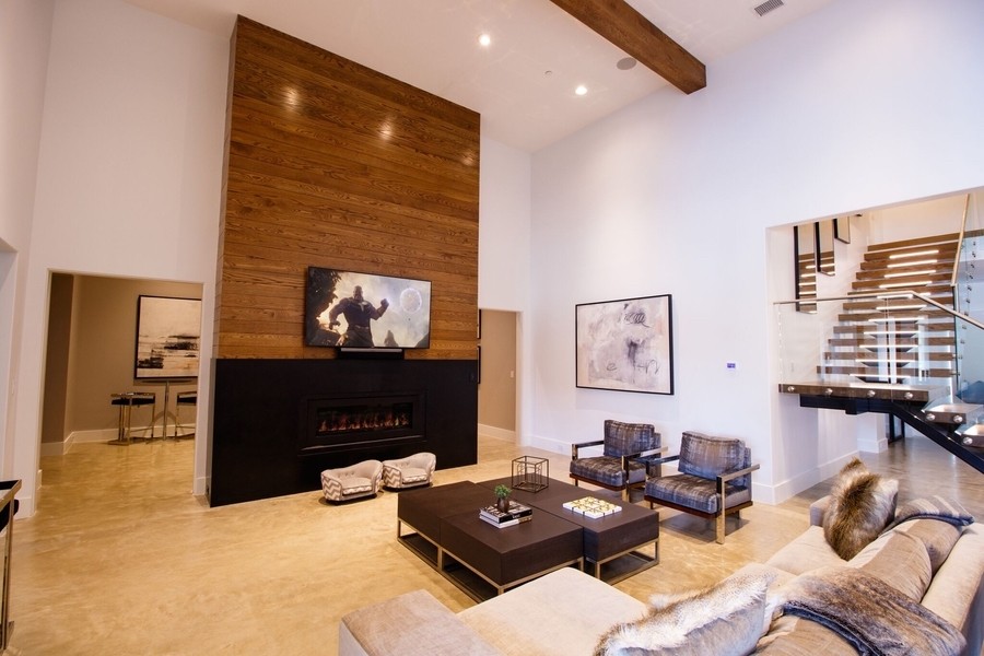 smart home living room with a large TV mounted above a fireplace, in-ceiling speakers, and smart lighting