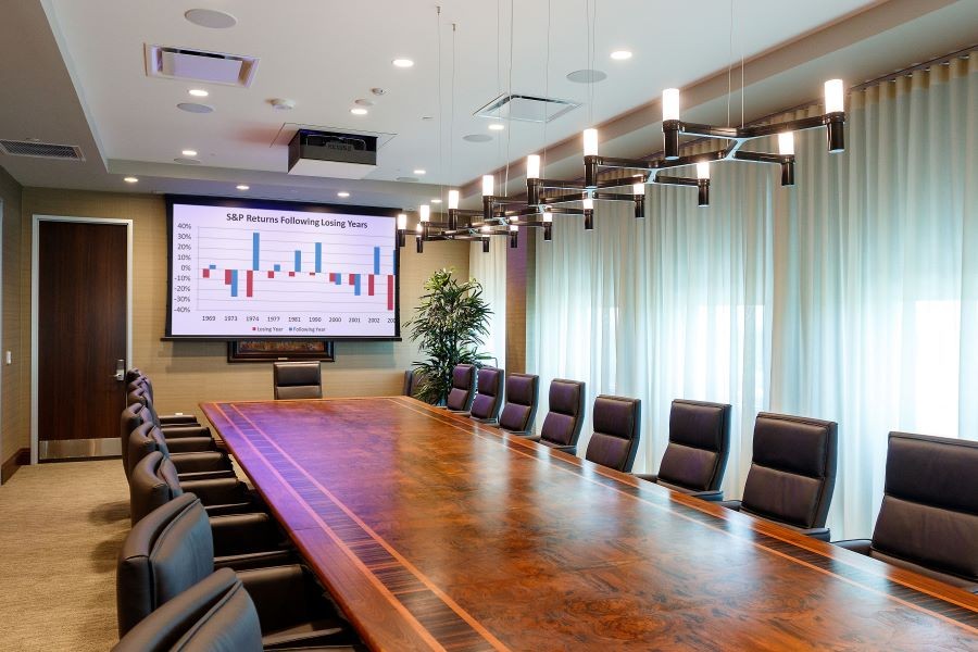 A boardroom with in-ceiling speakers, projector, and retractable screen.